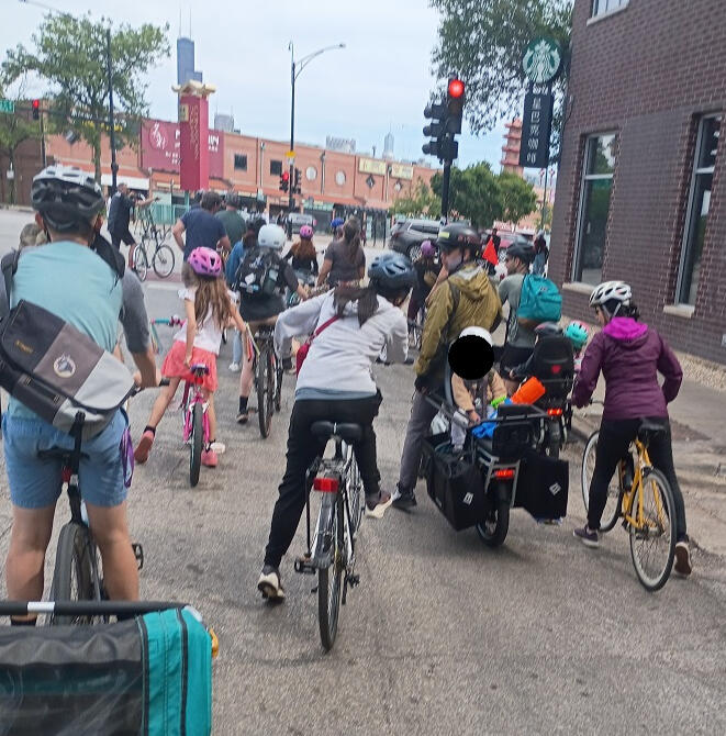 Children and adults on bikes shown from behind.