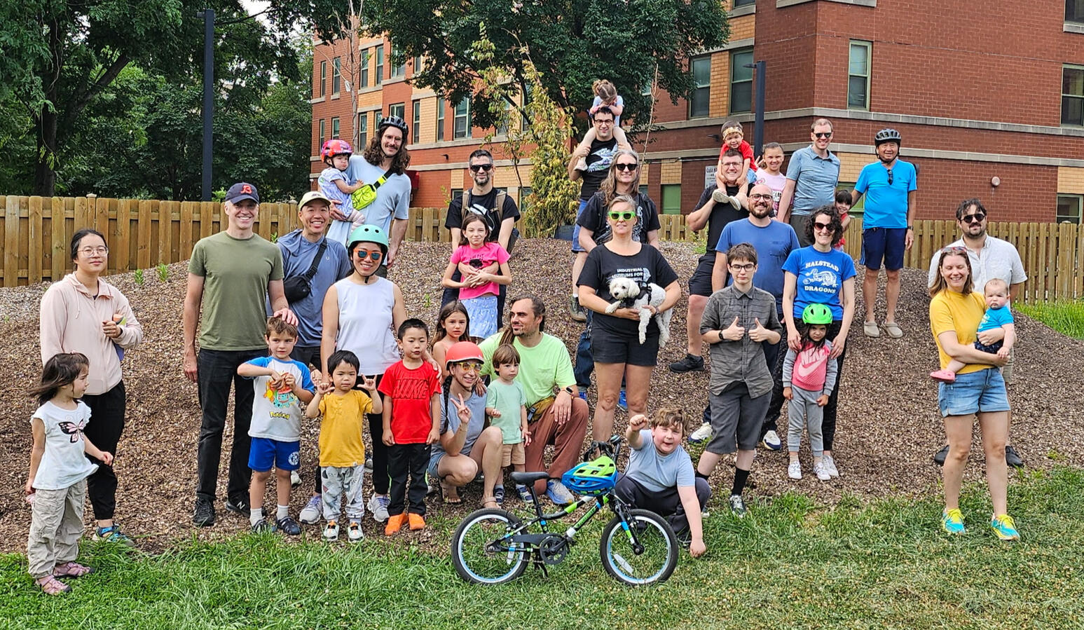 A few dozen people on a mulch pile with a bike up front.