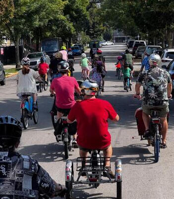 A mixed groups of people riding bicycles on a Chicago side street.